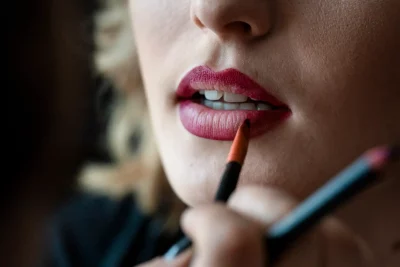 vue rapprochée sur la bouche d'une mariée à qui l'ont met du rouge à lèvres