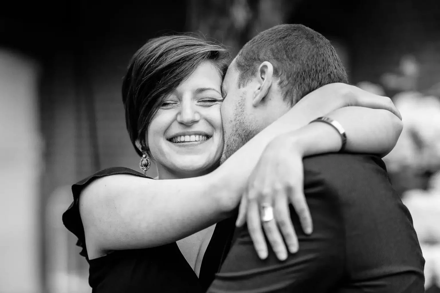 photo en noir et blanc d'un couple enlacé, la femme sourit tandis que son homme l'embrasse tendrement sur la joue