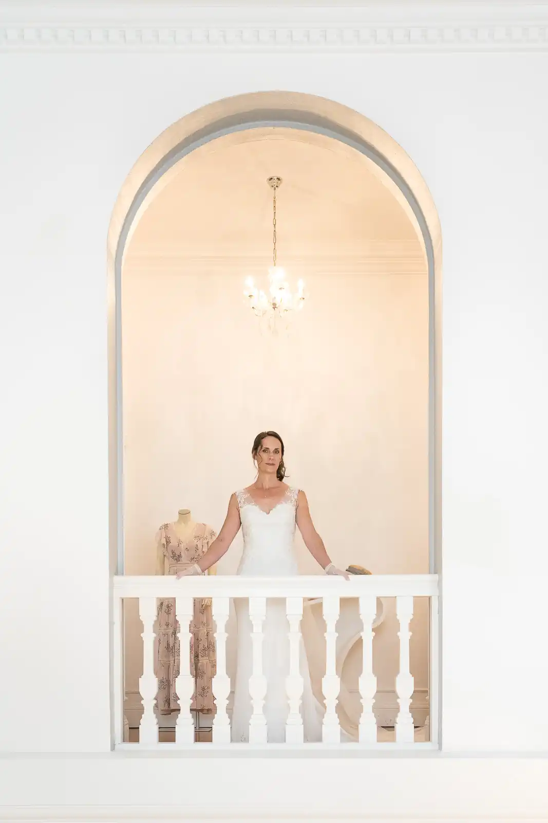 photo d'une femme en robe de mariée se tenant derrière une balustrade à l'intérieur d'un château