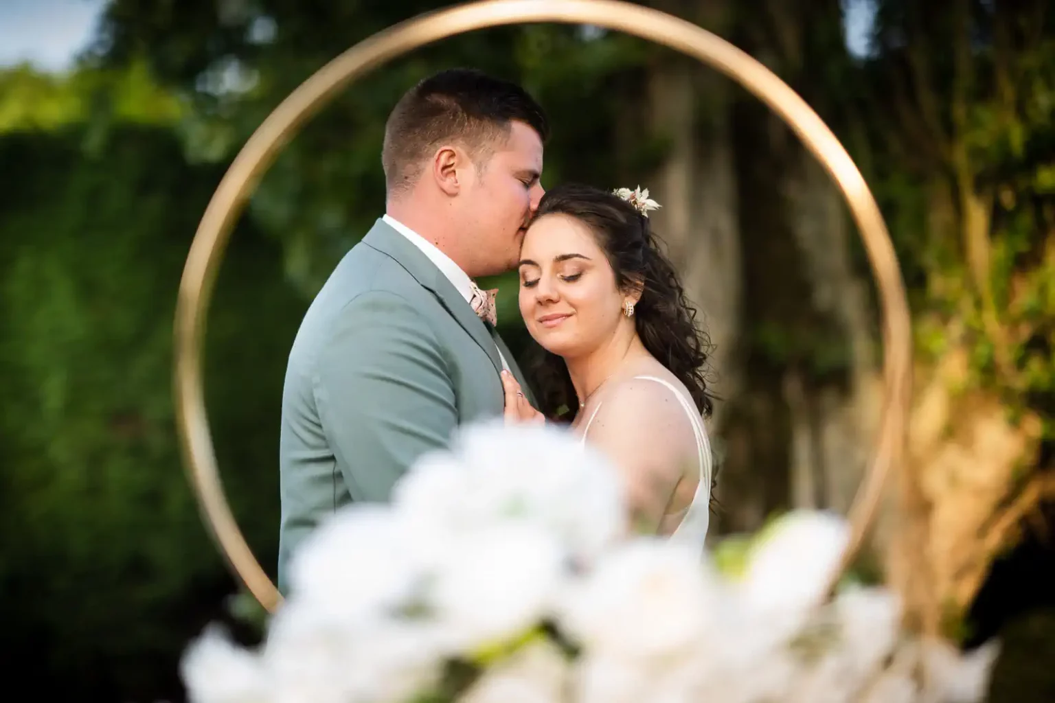 photo d'un couple de mariés posant dans le parc du domaine Le Comte à Hem. Ils sont enlacés, fermant les yeux, et apparaissent dans le cercle d'une bague