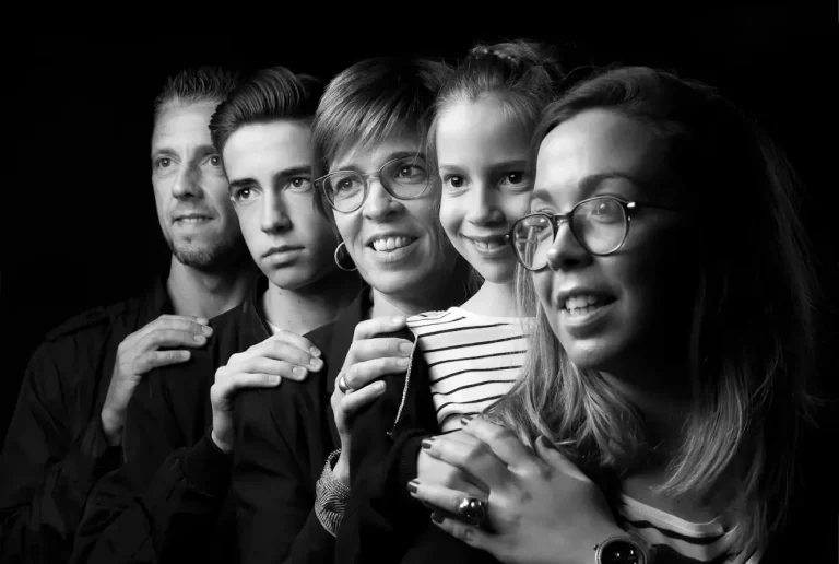 photo en noir et blanc d'une famille de 5 personnes qui se prennent dans les bras et regardent dans la même direction lors d'une séance photo