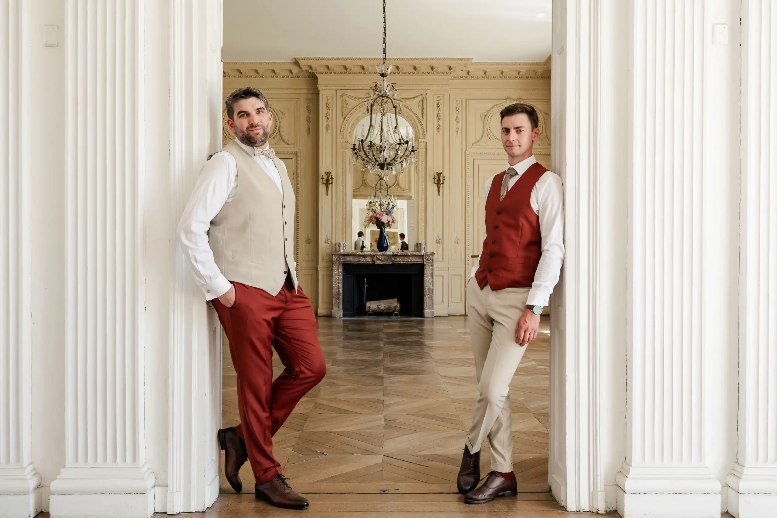 couple de mariés posant dans le salon d'un château lors de leur mariage. Ils sont habillés dans des couleurs beige et terracota